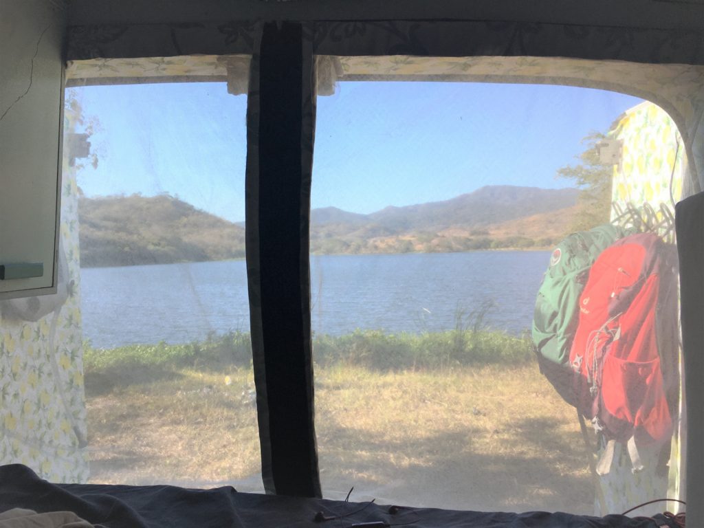 mosquito screen in rear doors of van in front of lake mountains