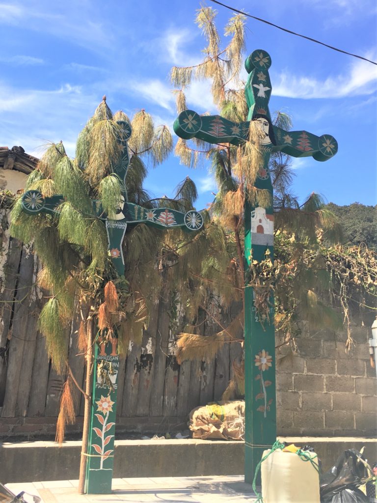 wooden mayan crosses draped in pine needles