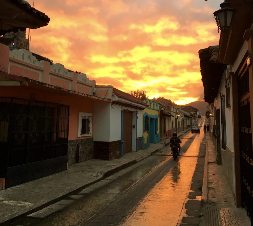 sunset over narrow street with motorcyclist