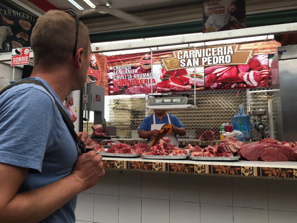 man standing in front of meat stall